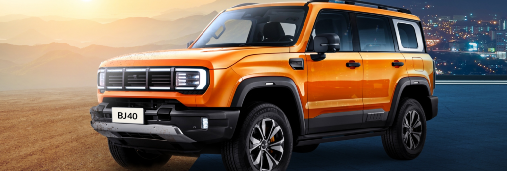 Der BAIC BJ40 Geländewagen in der Farbe Orange fährt durch unwegsames Gelände.